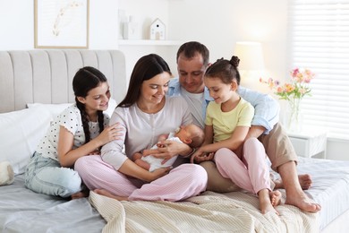 Photo of Happy family with newborn baby on bed at home