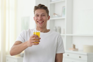 Photo of Smiling man with glass of orange juice at home. Refreshing drink
