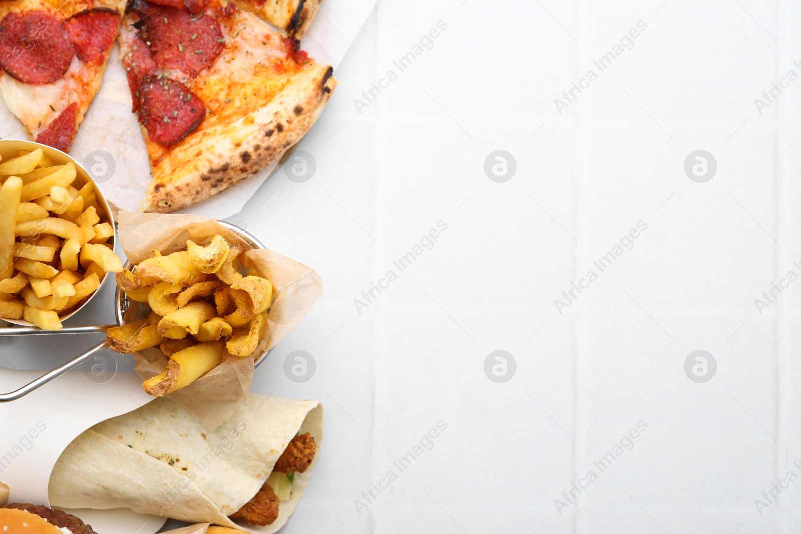 Different delicious fast food on white tiled table, flat lay. Space for text Photo of Different delicious fast food on white tiled table, flat lay. Space for text