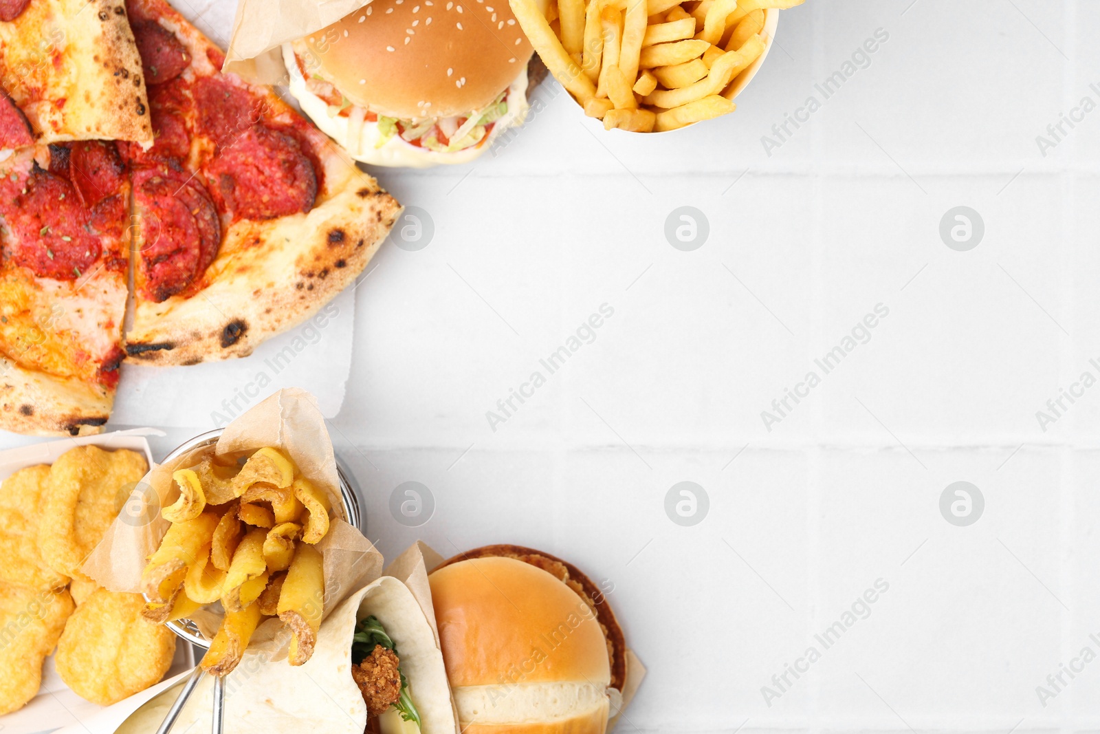 Different delicious fast food on white tiled table, flat lay. Space for text Photo of Different delicious fast food on white tiled table, flat lay. Space for text