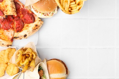 Photo of Different delicious fast food on white tiled table, flat lay. Space for text