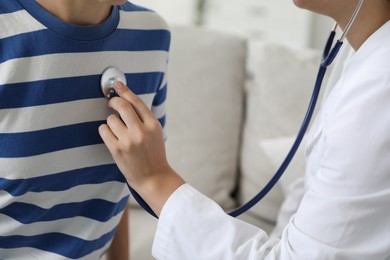Photo of Doctor checking woman's heartbeat with stethoscope indoors, closeup