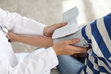 Photo of Doctor checking woman's heart rate and blood pressure via sphygmomanometer indoors, closeup