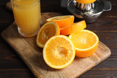 Photo of Freshly squeezed orange juice, fruits and juicer on wooden table, closeup