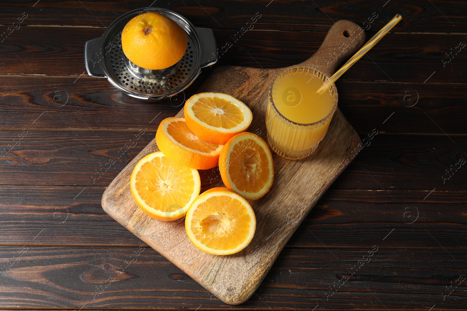 Photo of Freshly squeezed orange juice, fruits and juicer on wooden table, above view