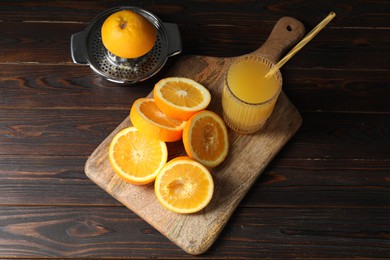 Photo of Freshly squeezed orange juice, fruits and juicer on wooden table, above view