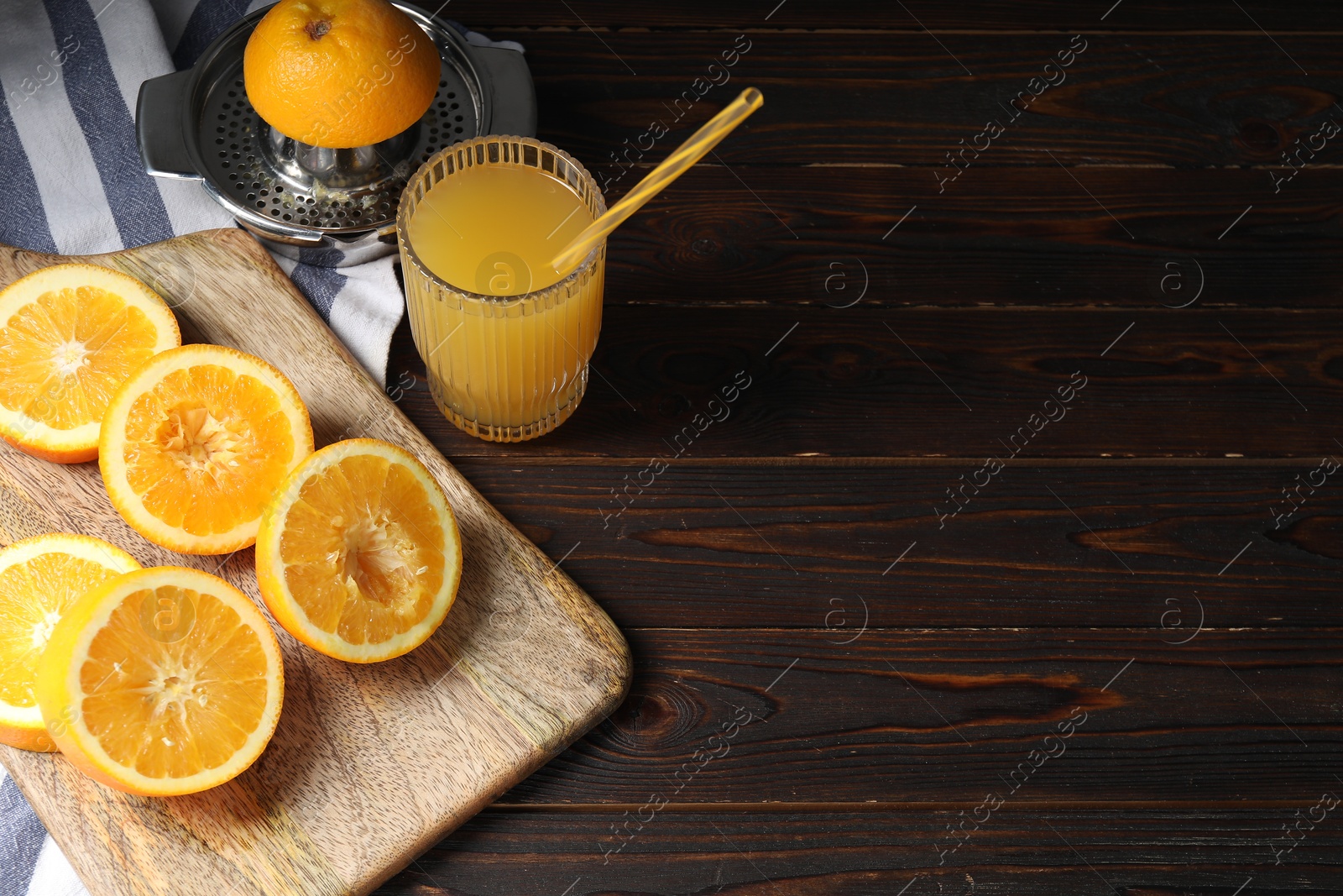 Photo of Freshly squeezed orange juice, fruits and juicer on wooden table. Space for text