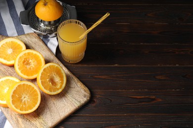 Photo of Freshly squeezed orange juice, fruits and juicer on wooden table. Space for text