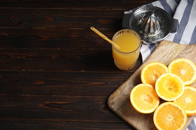 Photo of Freshly squeezed orange juice, fruits and juicer on wooden table. Space for text