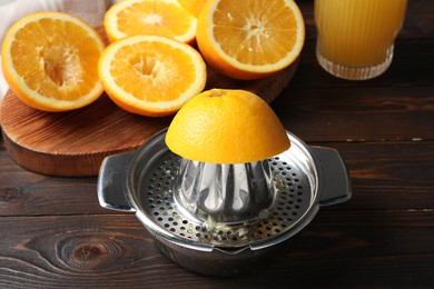 Photo of Squeezed oranges and juicer on wooden table, closeup