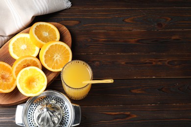 Photo of Freshly squeezed orange juice, fruits and juicer on wooden table, above view. Space for text