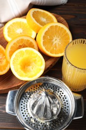 Photo of Freshly squeezed orange juice, fruits and juicer on wooden table, above view