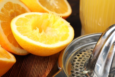 Photo of Freshly squeezed orange juice, fruits and juicer on wooden table, closeup