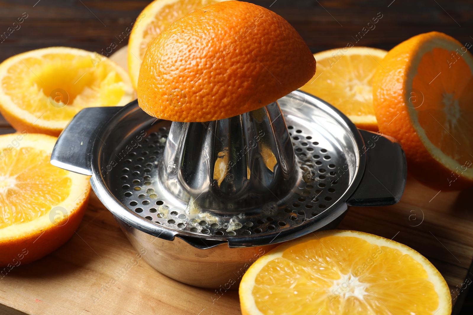 Squeezer with oranges on wooden table, closeup. Making fresh juice Photo of Squeezer with oranges on wooden table, closeup. Making fresh juice