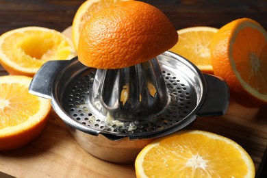 Photo of Squeezer with oranges on wooden table, closeup. Making fresh juice