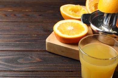 Photo of Freshly squeezed orange juice, fruits and juicer on wooden table, closeup. Space for text