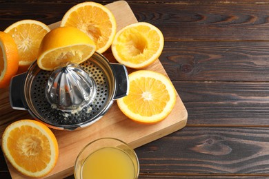 Photo of Freshly squeezed orange juice, fruits and juicer on wooden table, above view. Space for text
