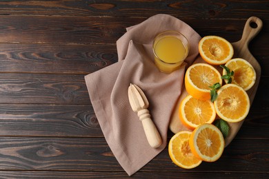 Photo of Freshly squeezed orange juice, fruits, juicer and towel on wooden table, flat lay. Space for text