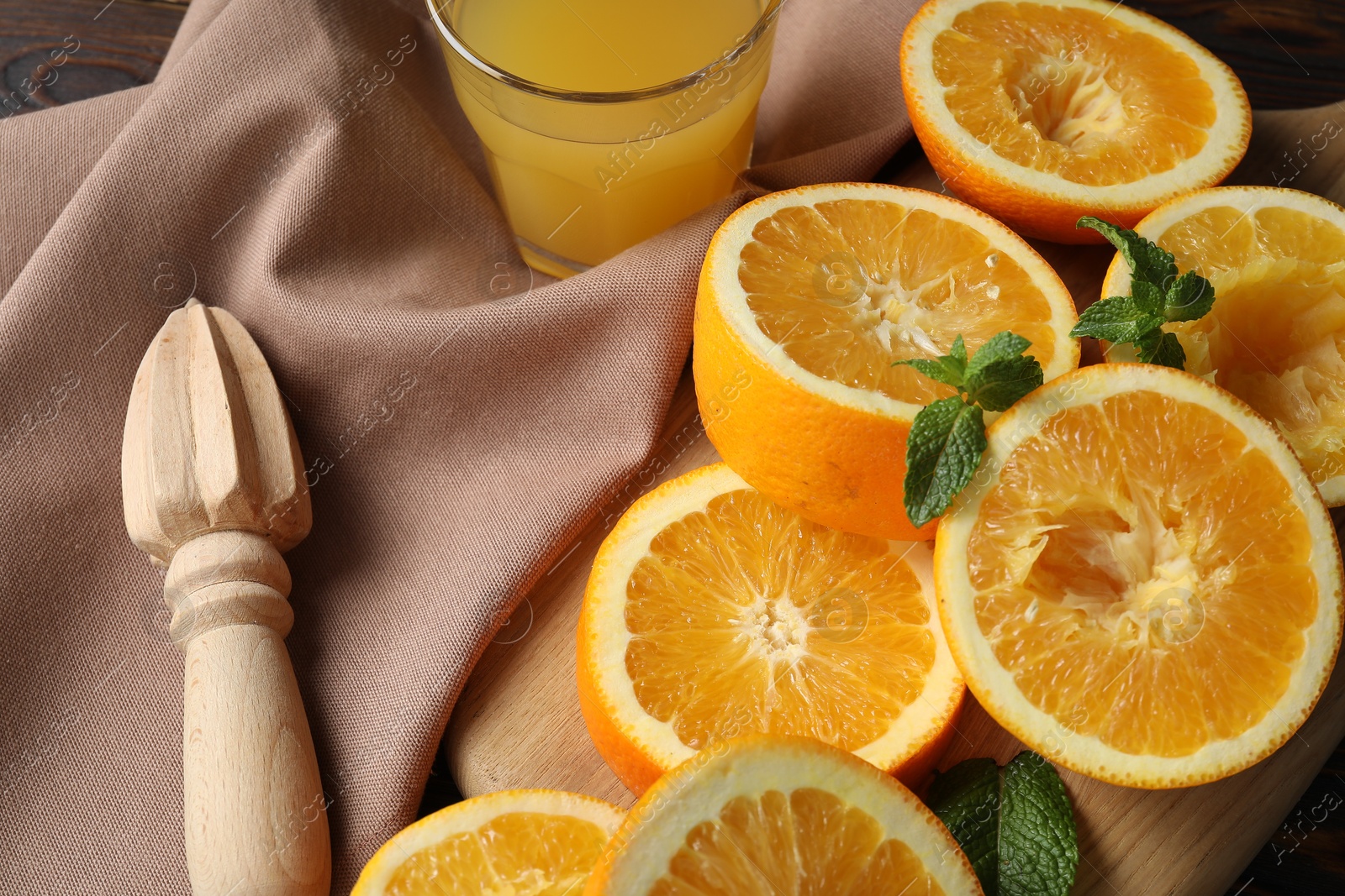 Freshly squeezed orange juice, fruits, mint, juicer and towel on wooden table, closeup Photo of Freshly squeezed orange juice, fruits, mint, juicer and towel on wooden table, closeup