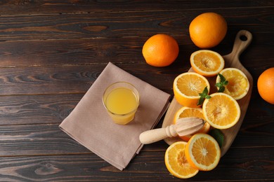 Photo of Freshly squeezed orange juice, fruits, mint, juicer and towel on wooden table, above view. Space for text