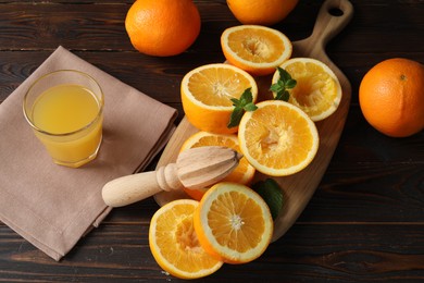 Photo of Freshly squeezed orange juice, fruits, mint and juicer on wooden table