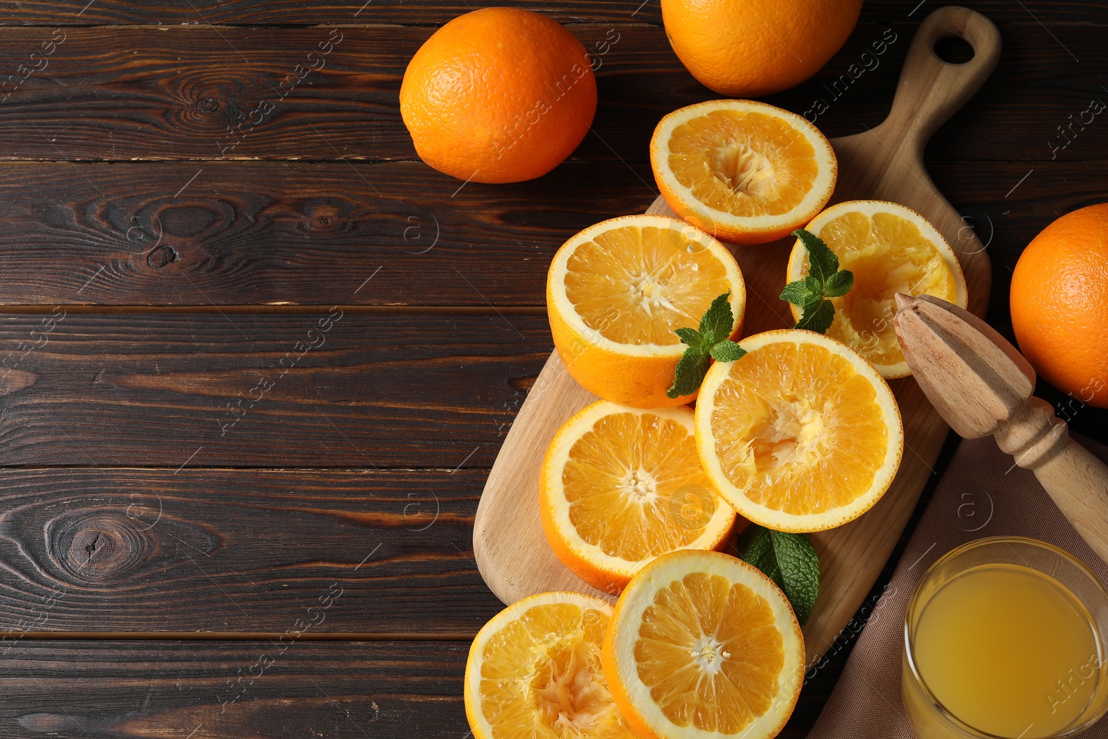Freshly squeezed orange juice, fruits with mint and juicer on wooden table, flat lay. Space for text Photo of Freshly squeezed orange juice, fruits with mint and juicer on wooden table, flat lay. Space for text