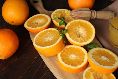 Photo of Squeezed oranges with mint and juicer on wooden table