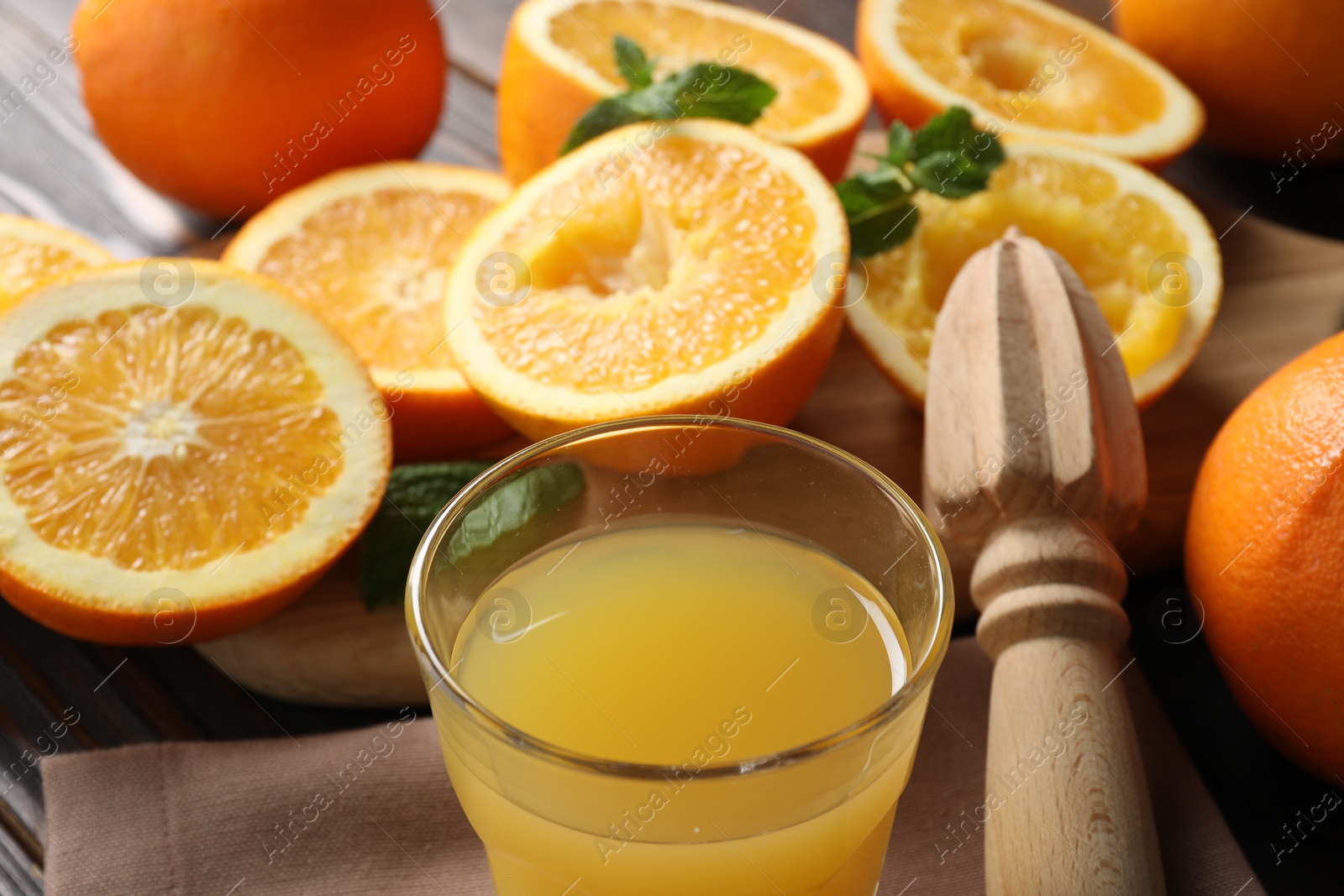 Freshly squeezed orange juice, fruits with mint, juicer and towel on table, closeup Photo of Freshly squeezed orange juice, fruits with mint, juicer and towel on table, closeup