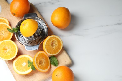 Photo of Squeezer, oranges and mint on white table, flat lay with space for text. Making fresh juice