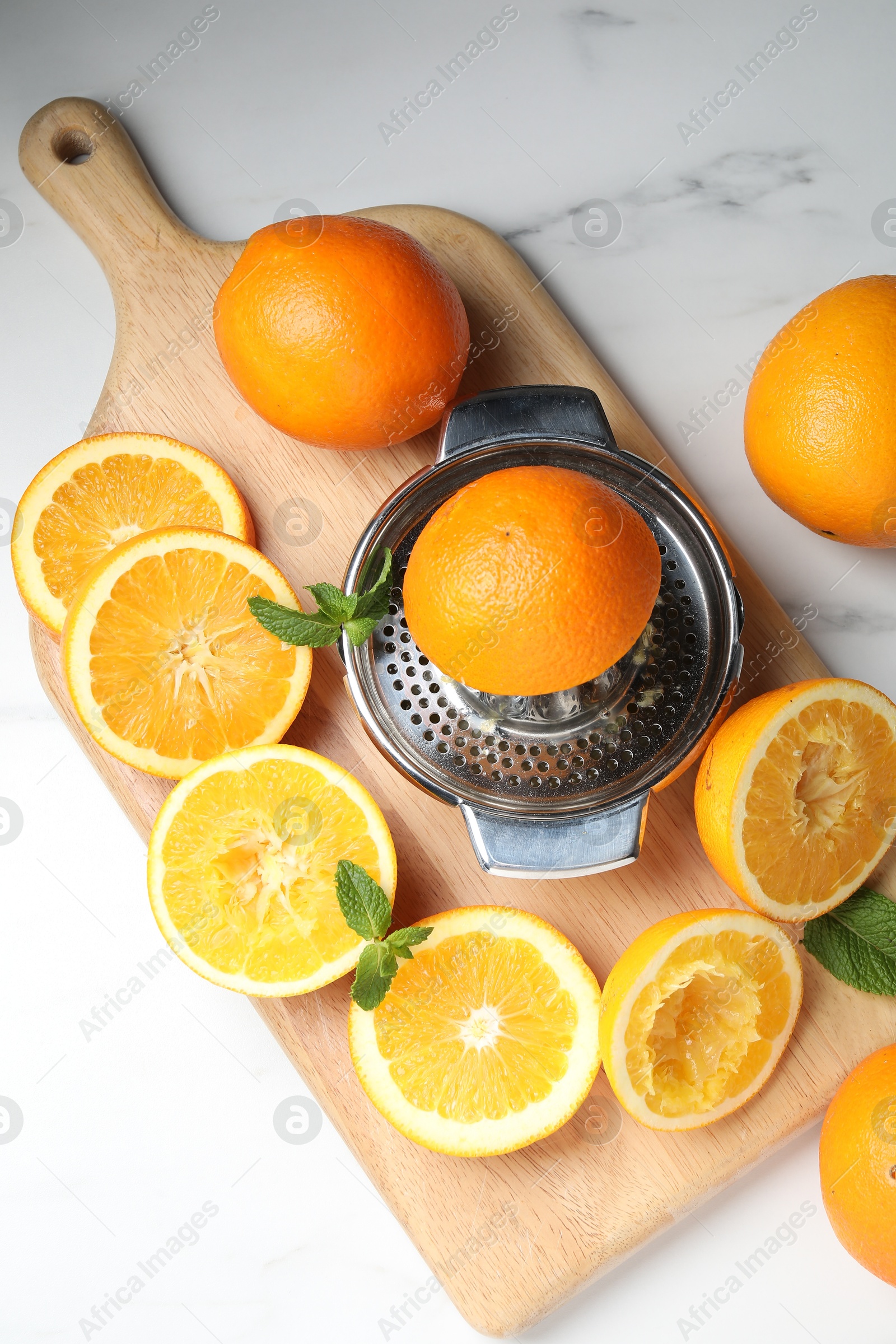 Squeezer with oranges and mint on white table, flat lay. Making fresh juice Photo of Squeezer with oranges and mint on white table, flat lay. Making fresh juice