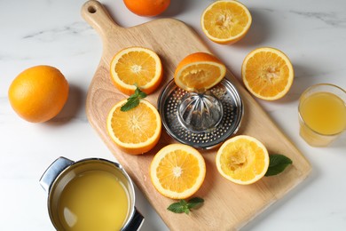 Photo of Squeezer with oranges, mint and fresh juice on white table, flat lay