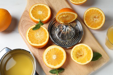 Photo of Squeezer with oranges, mint and fresh juice on white table, flat lay
