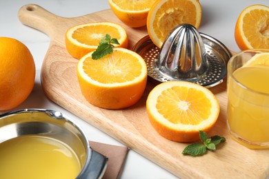Photo of Squeezed oranges with juicer and glass of juice on wooden table, closeup