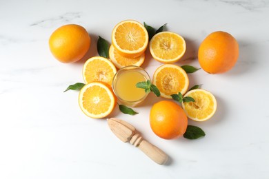 Photo of Freshly squeezed orange juice, fruits and juicer on white table, flat lay