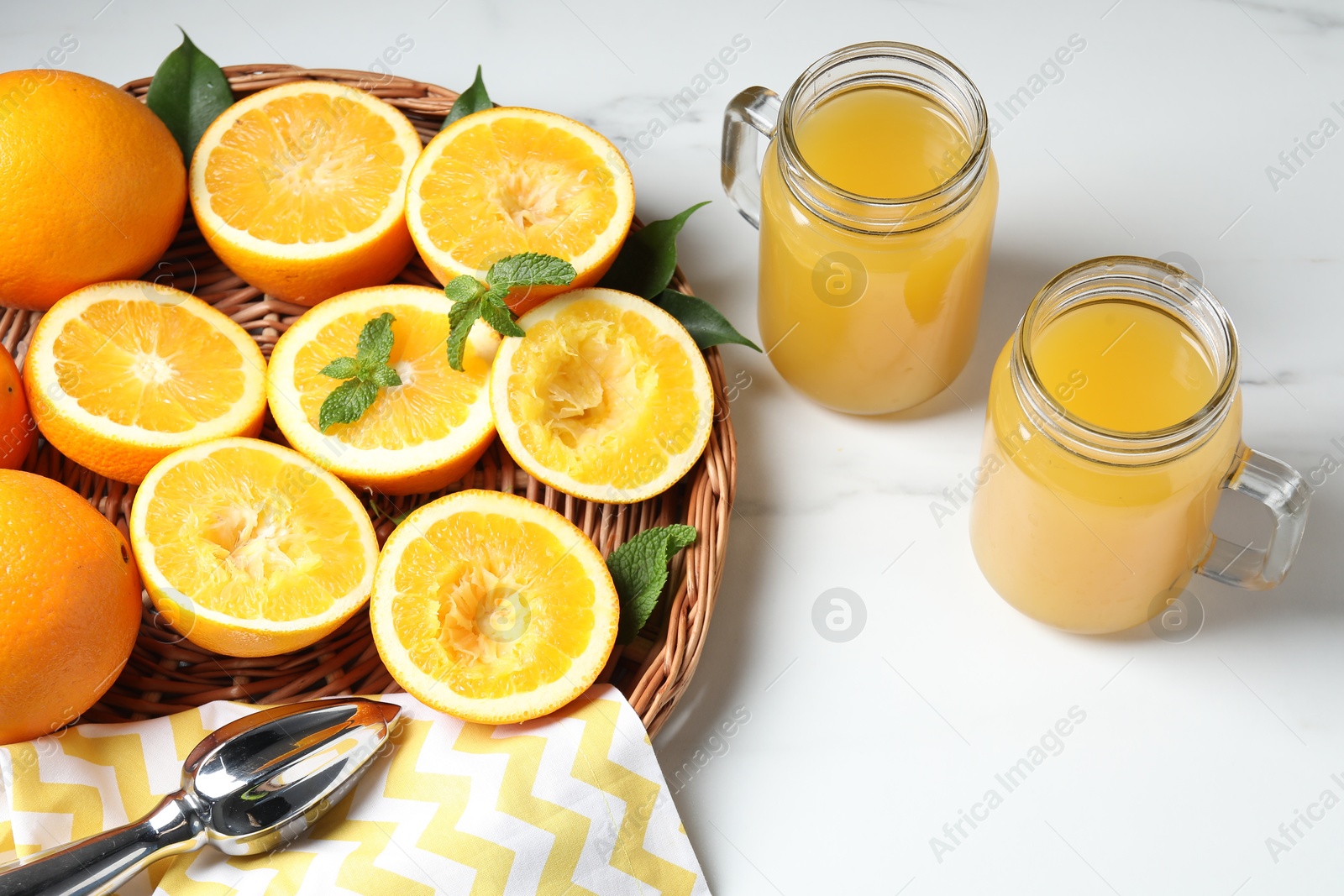 Photo of Freshly squeezed orange juice, fruits and juicer on white table