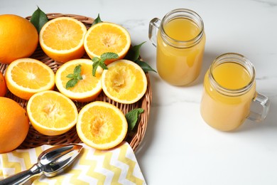 Photo of Freshly squeezed orange juice, fruits and juicer on white table