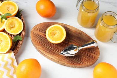 Photo of Freshly squeezed orange juice, fruits and juicer on white table, above view