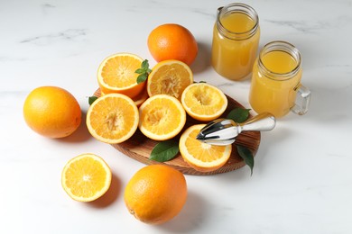Photo of Freshly squeezed orange juice, fruits and juicer on white table