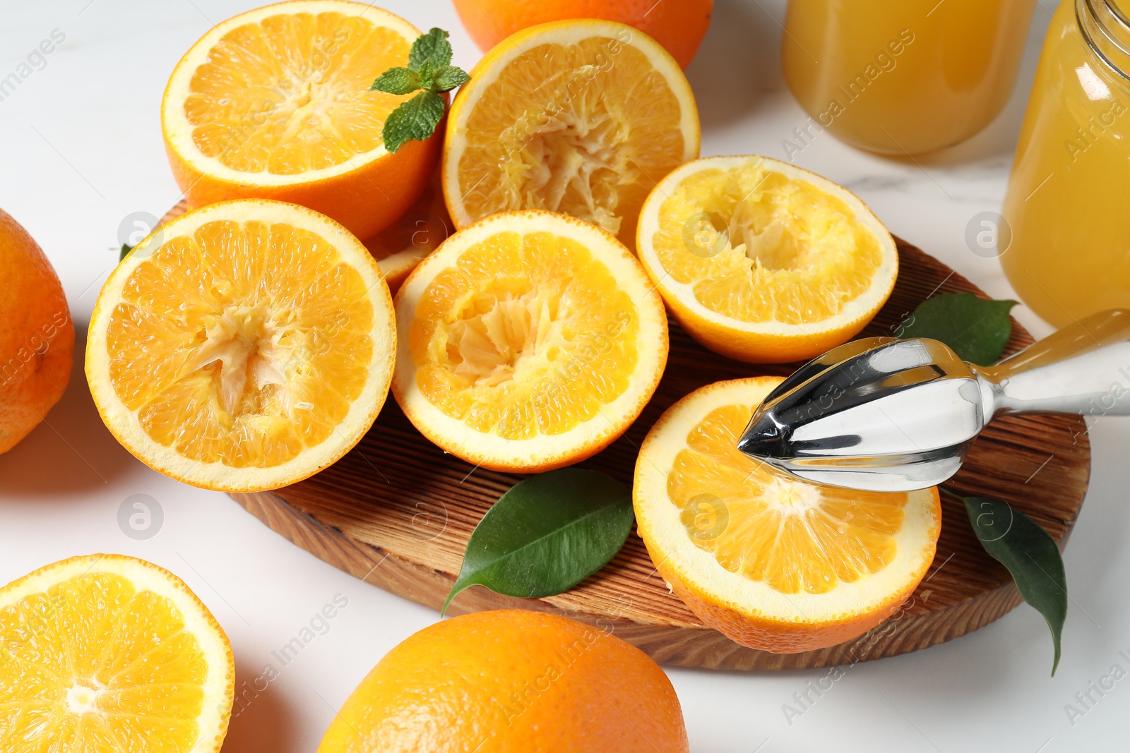 Photo of Squeezer, oranges and mint on white table, closeup. Making fresh juice