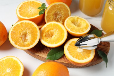 Photo of Squeezer, oranges and mint on white table, closeup. Making fresh juice