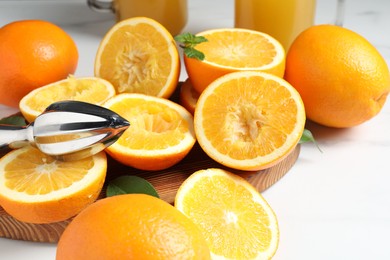 Photo of Squeezer, oranges and mint on white table, closeup. Making fresh juice