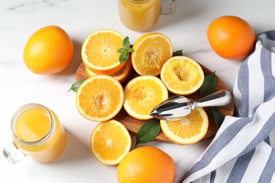 Photo of Freshly squeezed orange juice, fruits, juicer and towel on white table, flat lay