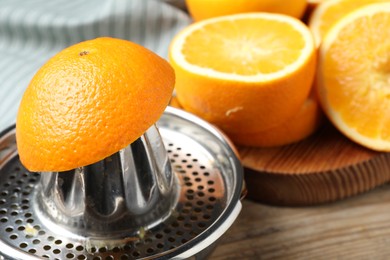Photo of Squeezer and oranges on wooden table, closeup. Making fresh juice