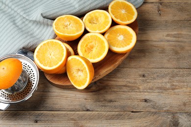 Photo of Squeezer and oranges on wooden table, flat lay with space for text. Making fresh juice