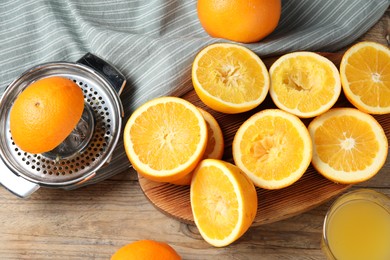 Photo of Freshly squeezed orange juice, fruits and juicer on wooden table, flat lay