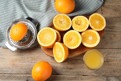 Photo of Freshly squeezed orange juice, fruits and juicer on wooden table, flat lay