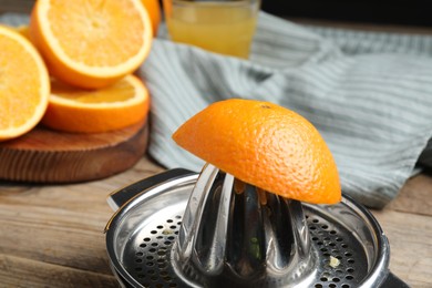 Photo of Squeezer and oranges on wooden table, closeup. Making fresh juice