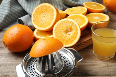 Photo of Freshly squeezed orange juice, fruits and juicer on wooden table, closeup