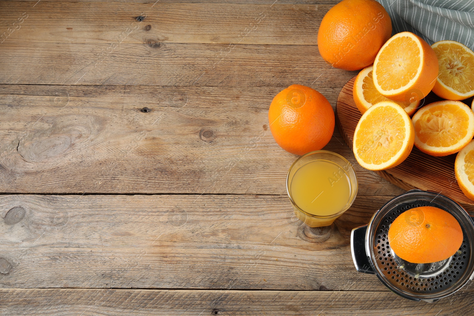 Photo of Freshly squeezed orange juice, fruits and juicer on wooden table, flat lay. Space for text