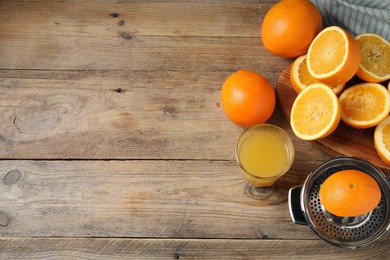Photo of Freshly squeezed orange juice, fruits and juicer on wooden table, flat lay. Space for text